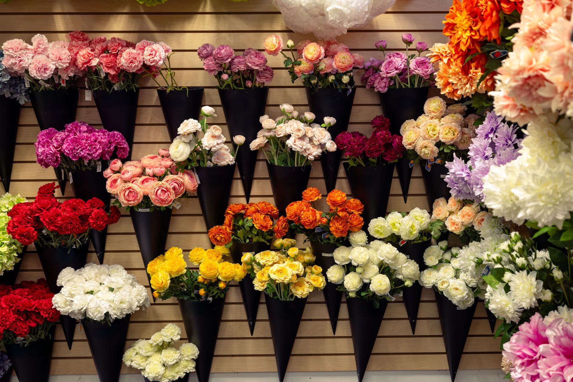Wall display of colorful flowers in black paper cones